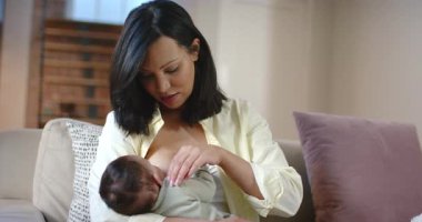 Anne gömleği çözüyor, oturma odasındaki kanepede yemek için memeleri ve beşiği teşhir ediyor. Annelik, bağlılık, beslenme, emzirme, şefkat, samimiyet, ev