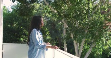 Afrika kökenli Amerikalı çiftler balkona bakıp ağaçları işaret ediyor ve beyaz metal korkulukları kucaklıyor. Romantik, sevgi, sükunet, açık hava, yaşam tarzı, manzara, bağlantı