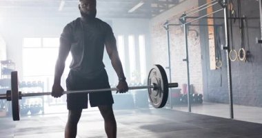 Adam spor salonunda dolu halterlere doğru yürüyor, temiz bir şekilde kaldırıyor ve kuvvet eğitimi için bastırıyor. Kuvvet, fitness, atletik, egzersiz, egzersiz, eğitim, endüstriyel