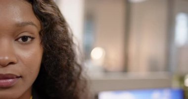 Kamera başlıyor, Afro-Amerikalı kadın başını sallıyor ve ofis masasına gülümsüyor, kopyalama alanı. Profesyonel, kurumsal, modern, minimalist, işyeri, teknoloji, pozitiflik