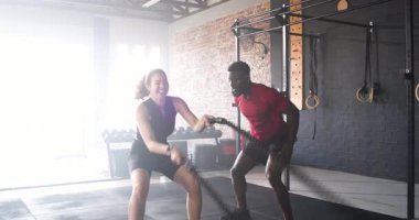 Antrenörlerin el ele tutuşması ve kadın müşterileri spor salonu inşaatında ip dalgaları yapmaya teşvik etmesi. Kuvvet, fitness, egzersiz, eğitim, kararlılık, performans, egzersiz