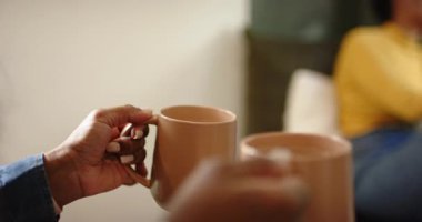 Asyalı Hintli kadın kahve ikram ediyor, Afro-Amerikalı arkadaşıyla kahve içiyor, pencerenin yanında yudumluyor. Arkadaşlık, konfor, sıcaklık, rahatlama, evcil, düşünceli, yaşam tarzı