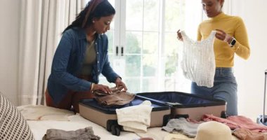 Yatakta açık bavulla, çeşitli bayan arkadaşlar pantolonlarını indiriyor, üstlerini katlıyor, yolculuk için eşyalarını topluyor. Seyahat hazırlığı, arkadaşlık, paketleme, organizasyon, günlük yaşam tarzı, uyum