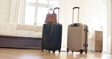 Kamera çerçeveli, el çantalı bavullar, yatak odasındaki sandalye ve sepeti gösteriyor. Bagaj, seyahat, zarafet, yaşam tarzı, iç mekan, minimalist, doku