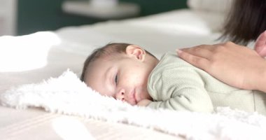 Bebek kızın göz kırpması, yatak odasındaki yumuşacık battaniyeyi yumuşatmak için annesinin bebeğin sırtını ovmasını tetikliyor. Bakıcı, terbiye, rahatlık, samimiyet, konforlu, ninni, bağ