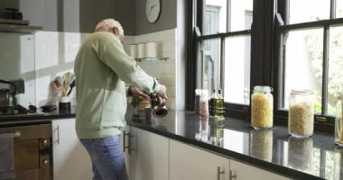 Afrikalı Amerikalı adam telefona bakıyor, Fransız basınıyla demleniyor, mutfak tezgahında fincana dökülüyor. Modern, yaşam tarzı, minimalizm, boş zaman, sıcak, gündüz, gündelik