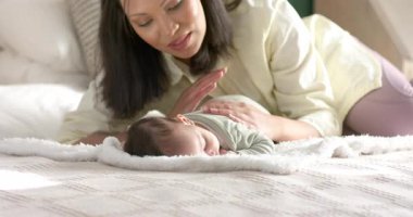 Yeni doğan bebeğe bakmak, evde yatağında uzanan bir kadın, rahatlamak için bebeğin sırtını okşamak. Annelik, şefkat, bağlılık, rahatlık, dinginlik, şefkat, şefkat