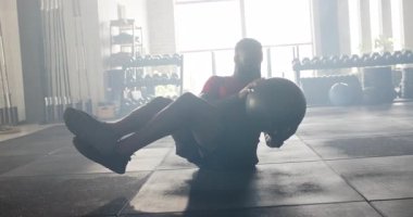 Spor salonuna girdiği için Afrikalı Amerikalı bir adam vücudunu bükmek için ilaç topunu tutuyor. Spor, spor, spor, antrenman, sağlık, atletizm