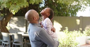 Kızı kollarını boynuna doladığında Afrikalı Amerikalı babası onu terasta kaldırıp çeviriyor. Aile, bağ, neşe, sevgi, açık hava, açık sözlü, şakacı
