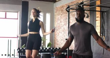 Çeşitli arkadaşlar halatlarla zıplıyor, dizlerini büküyor ve depo salonunda kardiyo için zıplıyorlar. Fitness, takım çalışması, güç, dinamik, modern, dayanıklılık, motivasyon