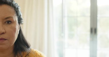 Sarı kazak giyen, gözlerini açan, gülümseyen, pencereye yaslanan, fotokopi çeken olgun bir kadın. Huzur, zarafet, doğal ışık, sıcaklık, farkındalık, gündelik konfor.