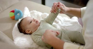 Anne sağdan giriyor, bebek kollarını indiriyor kanepede top ile hareket etmeye teşvik ediyor. Bakıcı, geliştirme, duyusal, besleyici, oyuncu, bağlantı, erken çocukluk