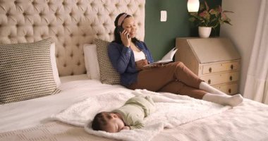 Midadult anne yatakta kitap okuyor. Akıllı telefonlara cevap veriyor. Bebeğe gülümsüyor. Aile, bakım, rahatlama, evcil, rahat, beslenme, yaşam tarzı