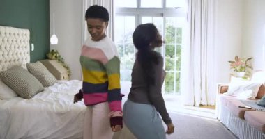 Çeşitli bayan arkadaşlar dans ediyor, dönüyor, yatağa yığılıyor ve güneşli yatak odasında gülüyor. Dinamik, dostluk, neşe, iç mekan, yaşam tarzı, hareket, konfor