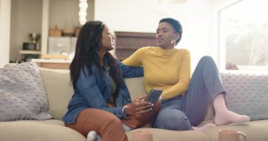 Farklı kadın partnerler akıllı telefonları kupaların yanında gösteriyor, kanepede karşılıklı konuşmalar yapıyorlar. Şefkat, samimiyet, bağlantı, sadakat, rahatlama, modern, gündelik