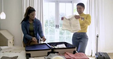 Çeşitli bayan arkadaşlar kıyafet sıralıyor, güneş gözlüğü deniyor, bavullarını hazırlıyor. Arkadaşlık, işbirliği, macera, gündelik, yaşam tarzı, hayat dolu, yerli