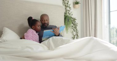 Açılış kitabı, Afrikalı Amerikalı baba ve kızı yorganın altına kıvrılıp, kitap okuyorlar. Aile, yakınlık, okur yazarlık, rahat, terbiye, ev, illüstrasyon