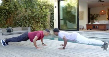 Erkek arkadaşlar güverteye girer, şınav çeker diz çöker ve havuz kenarında yukarı bakarlar. Fitness, yoldaşlık, açık hava, eğlence, dinamik, spor giyimi, motivasyon