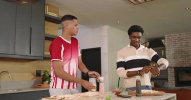 Çeşitli erkek arkadaşlar peynirleri öğütüyor, mutfak adasında pizza yiyip selfie çekiyorlar. İşbirliği, arkadaşlık, gündelik, modern, yaşam tarzı, mutfak, hazırlık