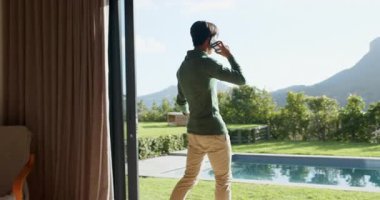 Asyalı adam yataktan akıllı telefonu kaldırıyor cam kapıdan giriyor, havuz başında volta atıyor. Açık hava, eğlence, yaşam tarzı, rahatlama, modern, sükunet, sağIık