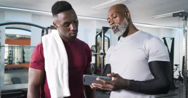Afrikalı Amerikalı antrenör ve müşteri spor salonundaki hedefleri gösteren tablet tıkırtı planına tepki veriyorlar. Fitness, akıl hocalığı, motivasyon, teknoloji, güç, sağlık, koçluk