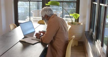 Ofise giren kıdemli Afrikalı Amerikalı adam dizüstü bilgisayarda yazmaya başlıyor, not defteri yazma notlarını açıyor. Konsantrasyon, verimlilik, çalışma alanı, modern, profesyonel, iç mekan, yaşam tarzı