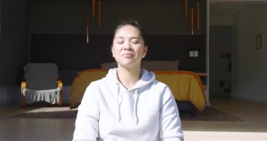 Nefes alıyor, akıllı Asyalı kadın kollarını kaldırıp dua ediyor, evde yoga yapmak için aşağı iniyor. Meditasyon, farkındalık, sağIık, sükunet, huzur, rahatlama, modern