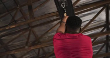 İp çeken Afrika kökenli Amerikalı bir adam, aşağı iniyor ve spor salonunda beşlik çakıyor. Spor, güç, takım çalışması, egzersiz, atletik, motivasyon, eğitim