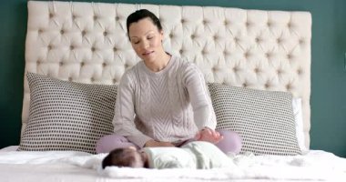 Anne kollarını kaldırmadan önce bebeğe dokunuyor ve yatak başlığının yanında sessizce meditasyon yapıyor. Bakıcı, yeni doğan, sükunet, bağlantı, rahatlama, konfor, farkındalık