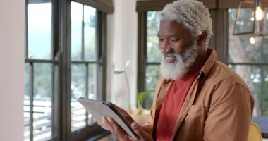 Kıdemli Afrikalı Amerikalı adam tablet alıyor ve evinde gülümsüyor, kopyalama alanı. Son sınıf, teknoloji, rahatlama, yaşam tarzı, ev, mutlu, dijital