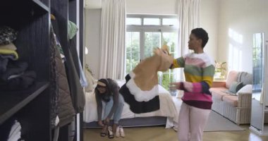 Çeşitli bayan arkadaşlar giyinip, topuklu ayakkabıları, yatak odasındaki topuklularla değiştirmeye çalışırken gardırobu tarıyorlar. Moda, arkadaşlık, tarz, iç mekan, rahat, hayat dolu, yaşam tarzı.