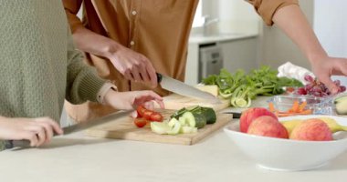 Bıçaklara uzanmak, salatalık doğramak ve salata hazırlamak için tezgahta domates kesmek. Aşçılık, aşçılık, takım çalışması, yerli, taze, sağlıklı, modern