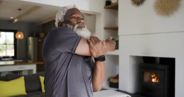 Afro-Amerikalı, spor tişörtlü, omuzlarını gevşetmek için kanepenin yanına uzanan olgun bir adam. Spor, sağlık, rahatlama, spor salonu, farkındalık, esneklik, kişisel bakım.