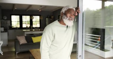 Beklerken balkona yaslanmış gülümseyen kıdemli Afro-Amerikalı adamı kontrol ediyorum. Modern, rahatlama, yaşam tarzı, rahatlık, gündelik, düşünce, teknoloji