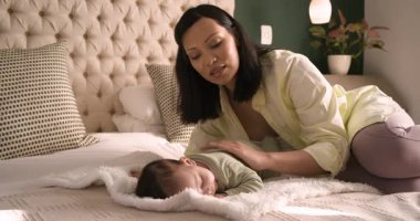 Solunumunu kontrol etmek için bakan Asyalı anne yatak odasındaki yumuşak battaniyeye nazikçe uyuyan bebeği okşuyor. Bakıcı, ninni, rahat, dinginlik, şefkat, beslenme, evcil