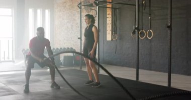 Spor salonunda müşteriye katılmadan önce antrenör müşteriye güç için halat sallıyor. Fitness, strength, training, motivasyon, group activities, movement, sport