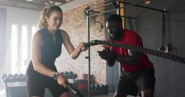 Afrika kökenli Amerikalı antrenör kadın müşteriye yol gösterirken beden eğitimi dersinde ip dalgaları yapıyor. Spor, güç, eğitim, dayanıklılık, motivasyon, egzersiz, endüstriyel