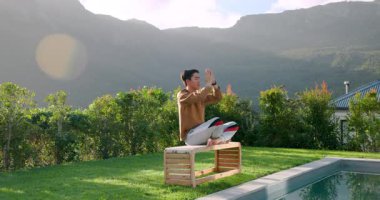 Havuzda parlayan güneş ışığı Asyalı adama yol gösteriyor. Yedek kulübesine adım atıyor. Meditasyon için kollarını kaldırıyor. Dinginlik, tefekkür, farkındalık, sükunet, sağlık, doğal, açık hava.