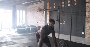 Ön raftan, sporcu bacaklarının arasından geçiyor ve beden eğitimi dersinde halterlere bastırıyor. Güç, zindelik, güç, spor salonu, antrenman, egzersiz, hareket