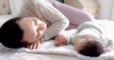 Yetişkin bir anne başını küçük kızına çeviriyor, yatakta romper okşuyor, rahatlık sağlıyor. Bakım, bakım, şefkat, aile, şefkat, bağ, yatma zamanı