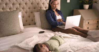 Anne dizüstü bilgisayarda yazarak ve yatağın başındaki uyuyan kızına bakarak işini bitiriyor. Bakıcı, aile, konforlu, evcil, çalışma alanı, konfor, bakım