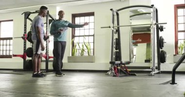 Afrika kökenli Amerikalı erkekler spor salonuna giriyor ve çıkmadan önce tablet tablet üzerinde egzersiz planlarını tartışıyor. Fitness, antrenman, güç, spor salonu, atlet, egzersiz, kararlılık