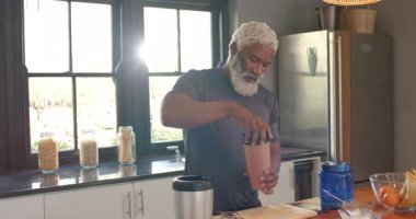 Afrika kökenli yaşlı bir Amerikalı 'yı karıştırıcı bardağa takviye doldurup tezgahta karıştırarak uyandırmak. Sağlıklı, beslenme, mutfak, yaşam tarzı, sağlık, modern, doğal