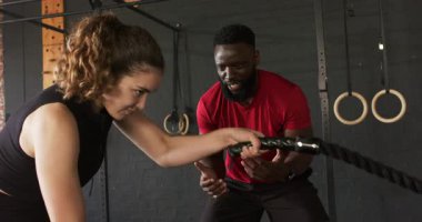 Antrenörde bayan müşteri güç için spor salonunun zeminine halat vuruyor. Kopya alanı. Spor, güç, antrenman, kondisyon, spor, azim