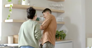 Bir çift, ellerini duruladıktan, kereviz ve salatalık dilimledikten sonra mutfak adasında şakacı dokunuşlar yapıyor. Romantizm, samimiyet, evcil, yaşam tarzı, modern, aşçılık, ortaklık