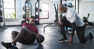 Afrikalı Amerikalı erkek stajyer tıp topu seçiyor, beden eğitimi dersinde gövde büküyor. Spor, güç, antrenman, sağlık, atletik, motivasyon