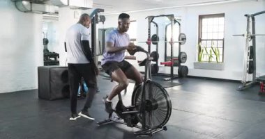 Antrenörden sonra Afrikalı Amerikalı erkek müşteri spor salonunda spor yapmak için pedal çeviriyor. Egzersiz ekipmanları, fitness, kuvvet, dayanıklılık, motivasyon, profesyonel, spor