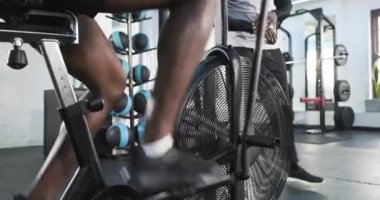 Afrikalı Amerikalı erkek antrenör, spor salonunda bisiklet sürerken saat fitness zamanlayıcısına başlıyor. Dinamik, performans, motivasyon, güç, sağlık, egzersiz, modern