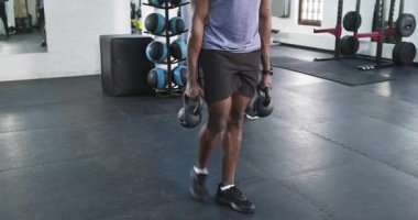 Afrika kökenli Amerikalı antrenör stajyerin arkasına geçip spor salonunda kettlebell sallıyor. Spor, spor, motivasyon, dayanıklılık, atletizm