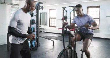 Afrika kökenli Amerikalı bir adam spor salonunda pedal çeviriyor. Koçun güç için işaret verişi, fotokopi alanı. Eğitim, fitness, power, motivasyon, spor salonu, sağlık, egzersiz